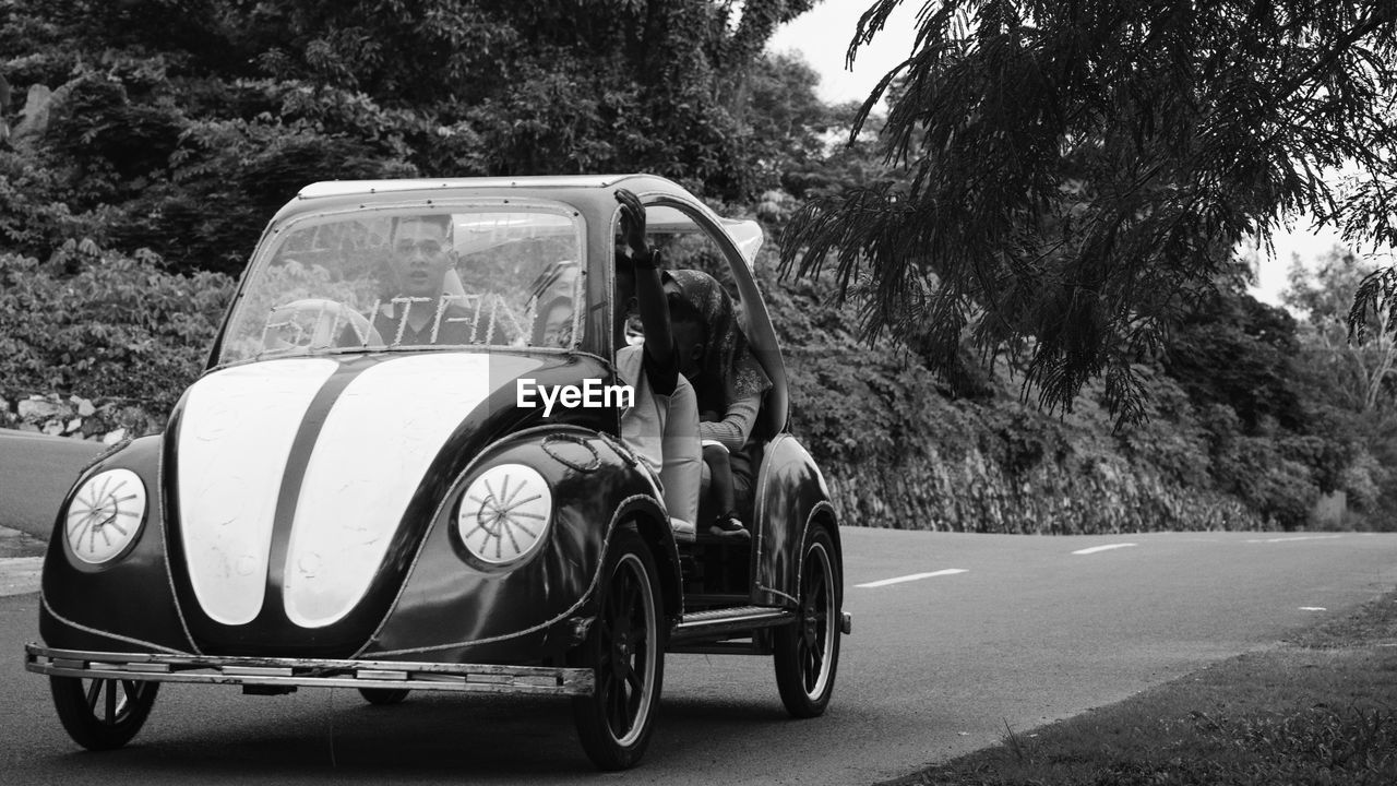 People sitting in vintage car on road