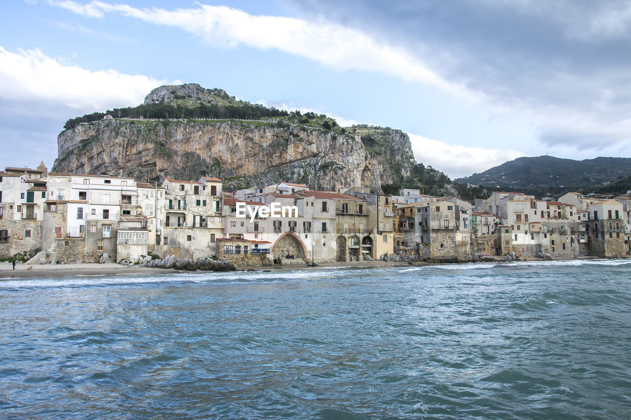 Buildings by sea against sky in city