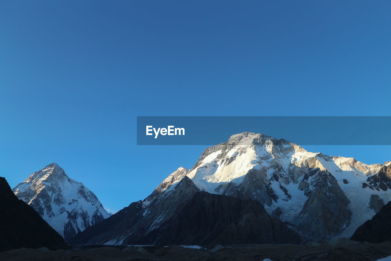 Scenic view of snowcapped mountains against clear blue sky