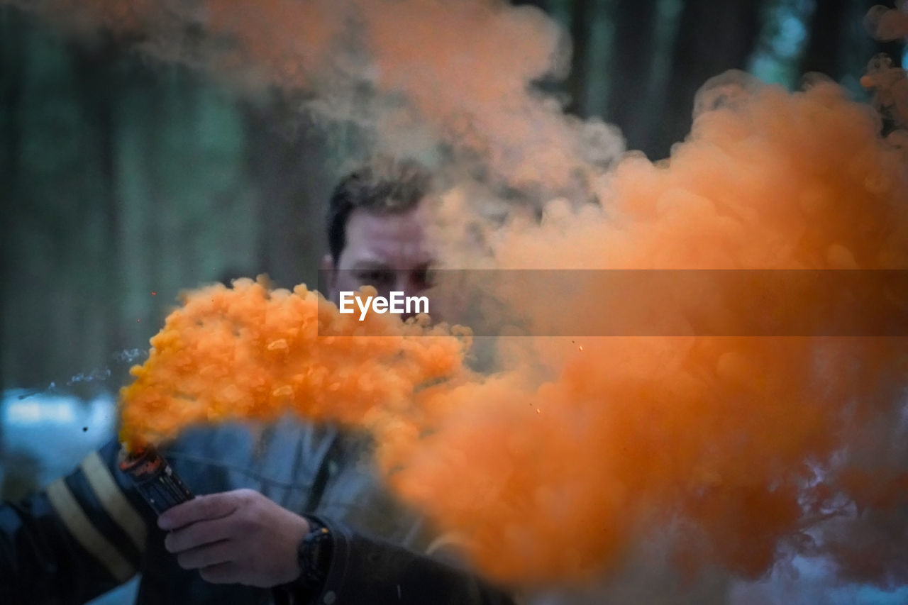 Man with orange smoke emitting from distress flare