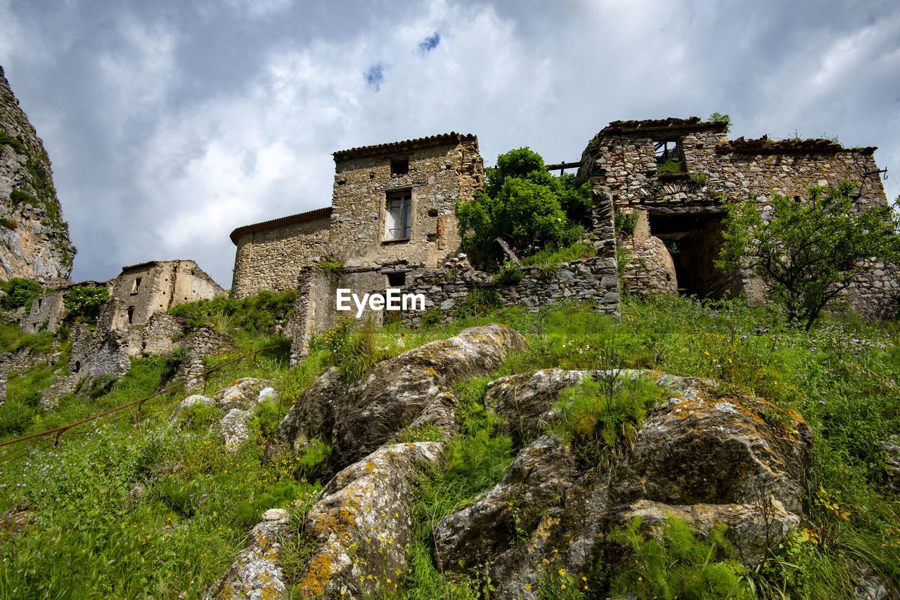 ruins, architecture, history, sky, cloud, the past, built structure, nature, rock, building exterior, building, ancient, old ruin, travel destinations, castle, plant, travel, land, old, no people, landscape, stone material, fortification, tourism, wall, ancient history, medieval, rural area, outdoors, environment, house, ruined, cliff, tree, village, scenics - nature, terrain, château, grass, fort, hill, stone wall, ancient civilization, low angle view, non-urban scene, beauty in nature, day, abandoned
