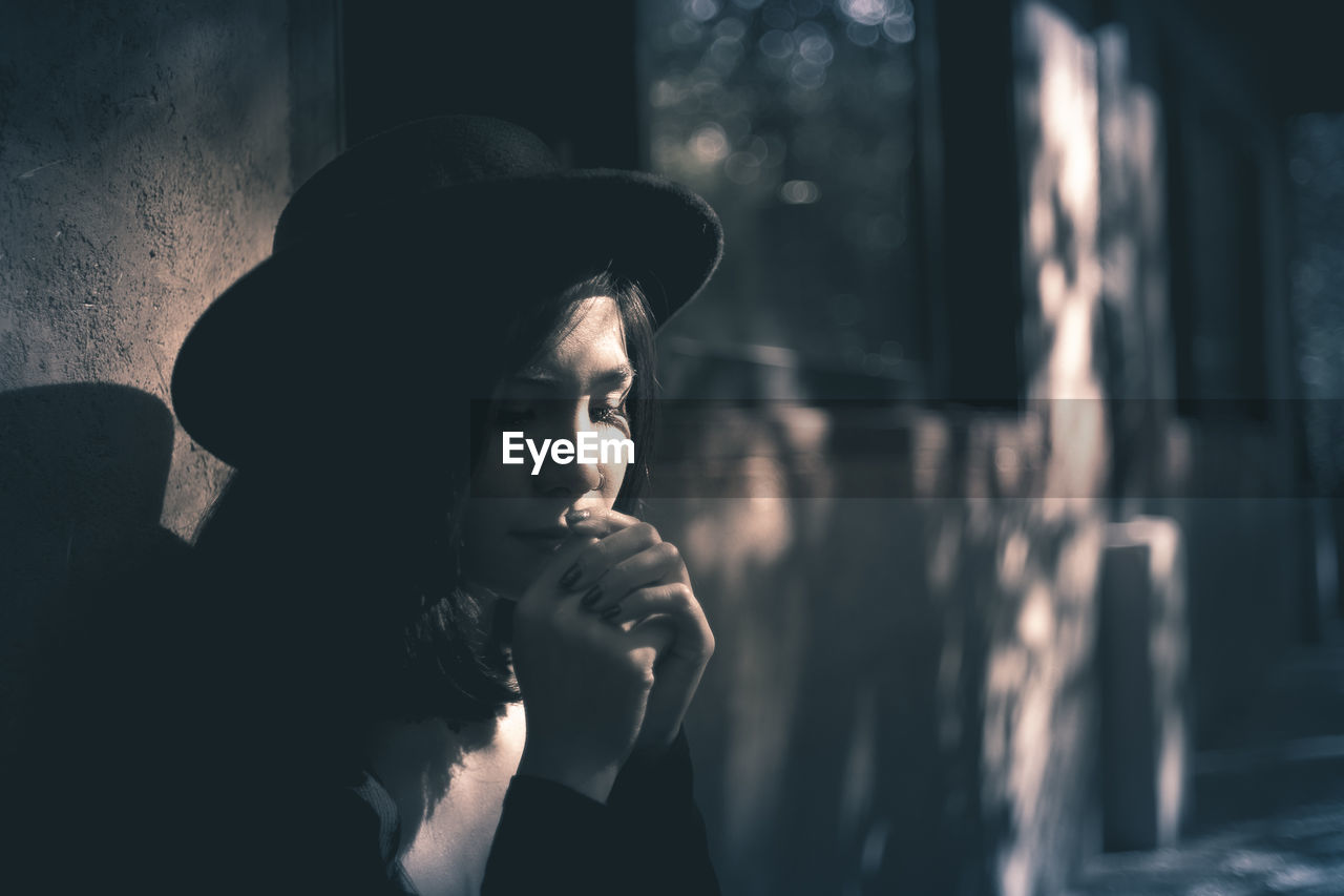 Thoughtful woman in hat by window