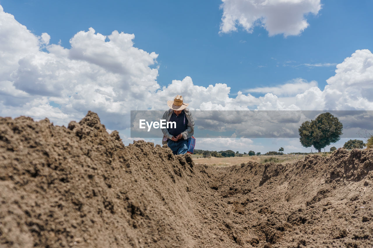 Rear view of man walking on field against sky