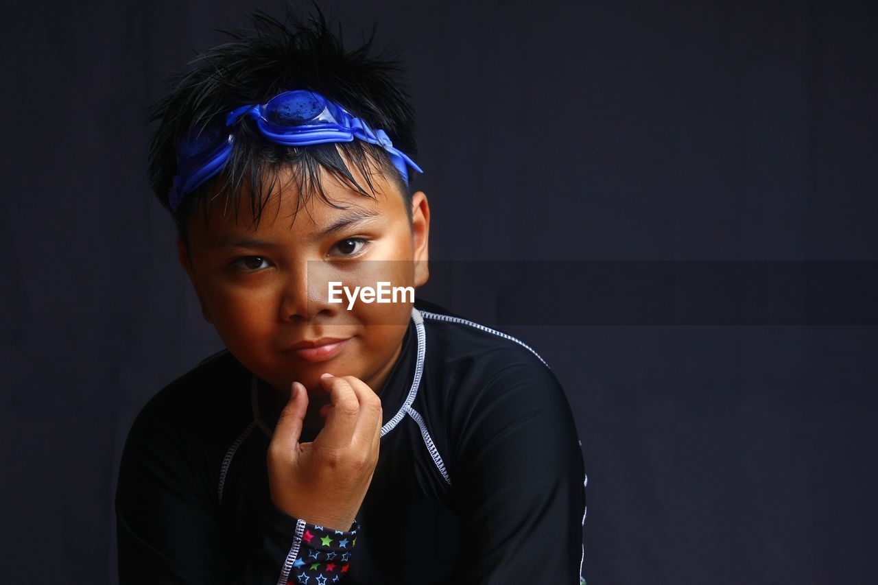 Portrait of boy against black background