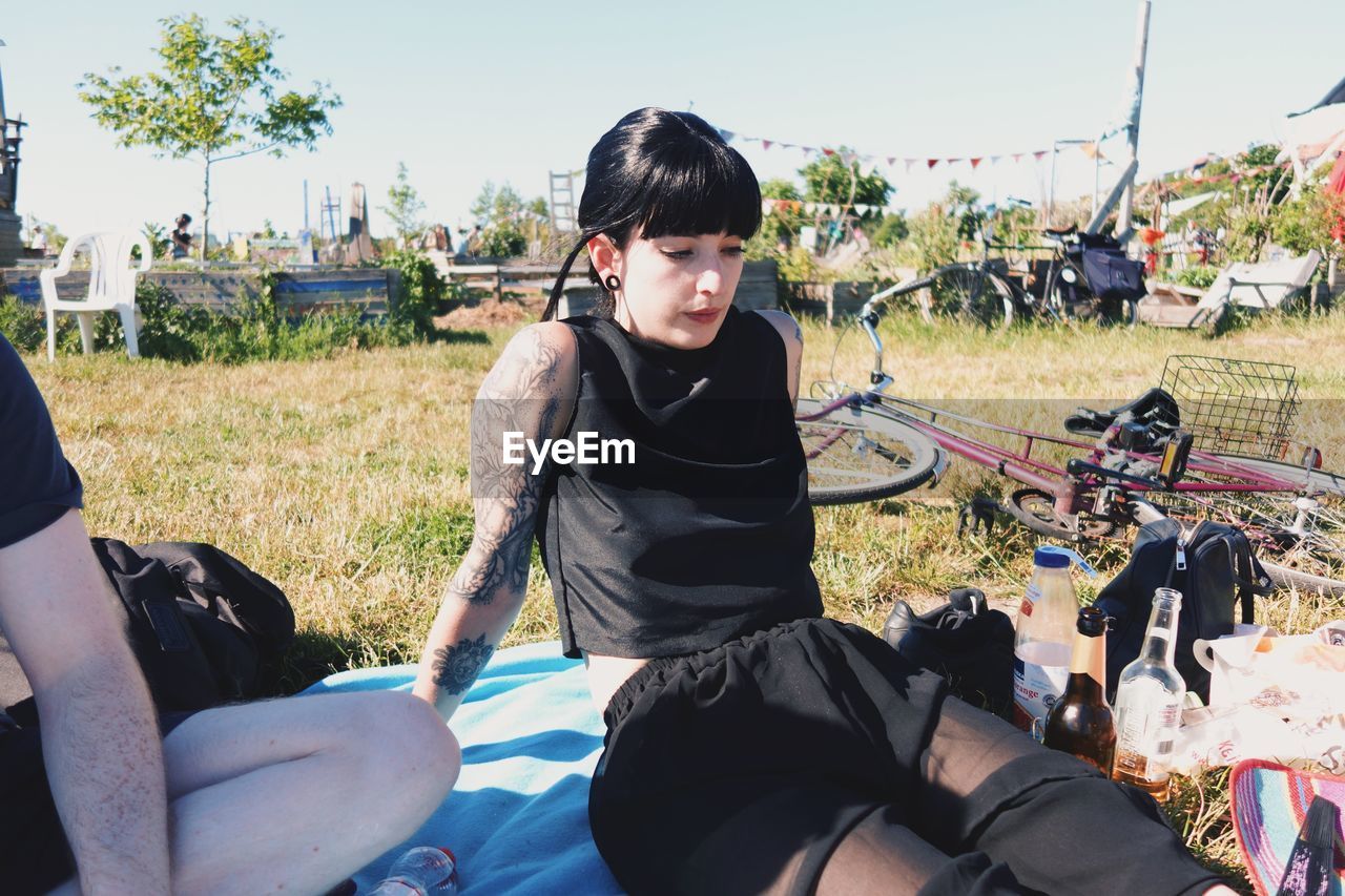 Portrait of goth woman sitting on field against clear sky