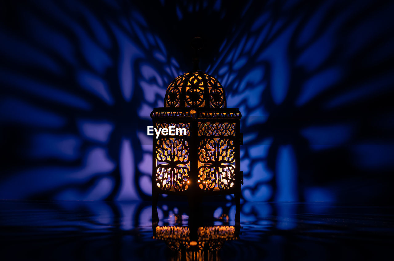 Black lantern with reflection from blue background for the holy month of ramadan kareem.