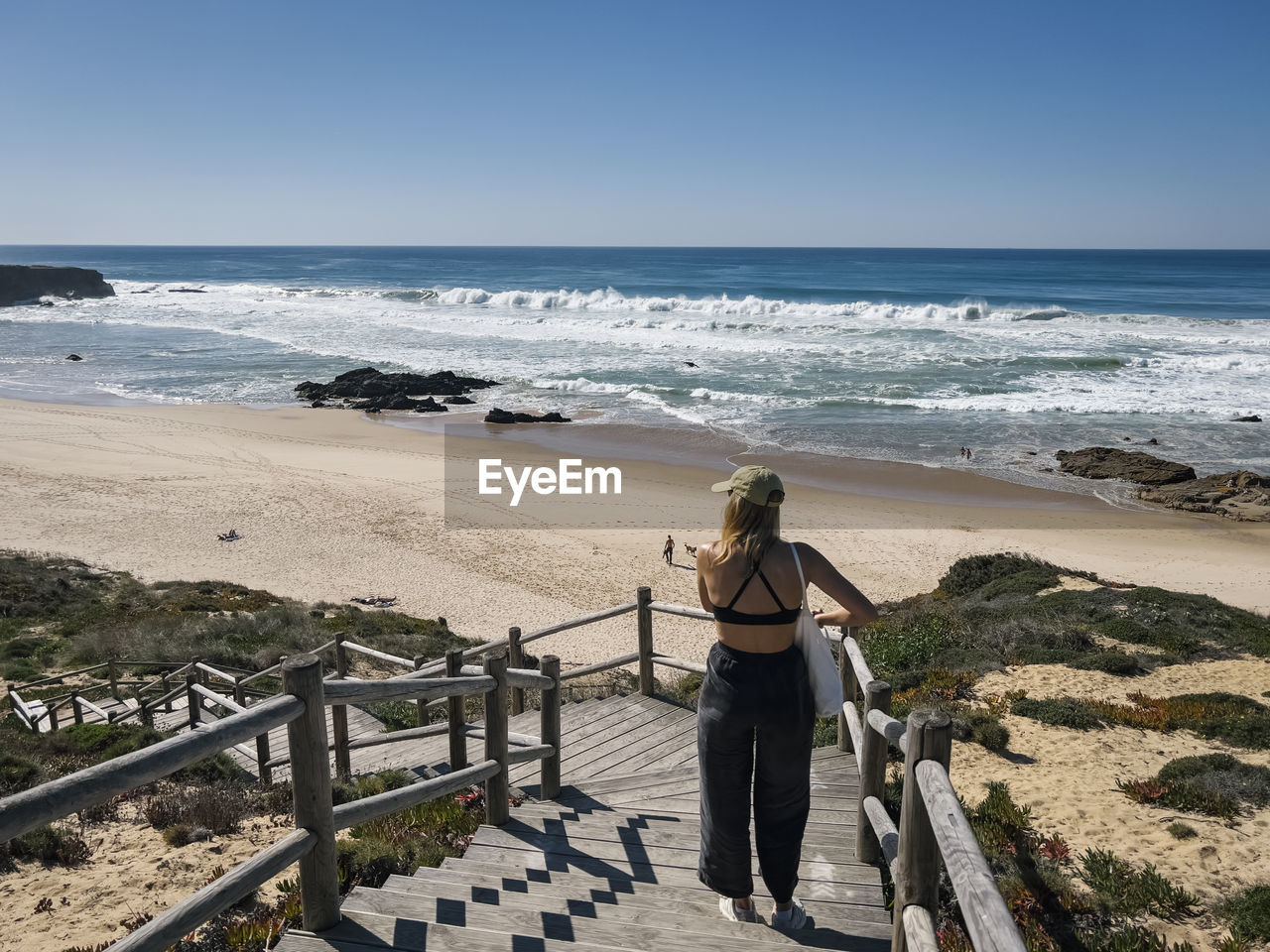 rear view of woman walking on beach against clear sky