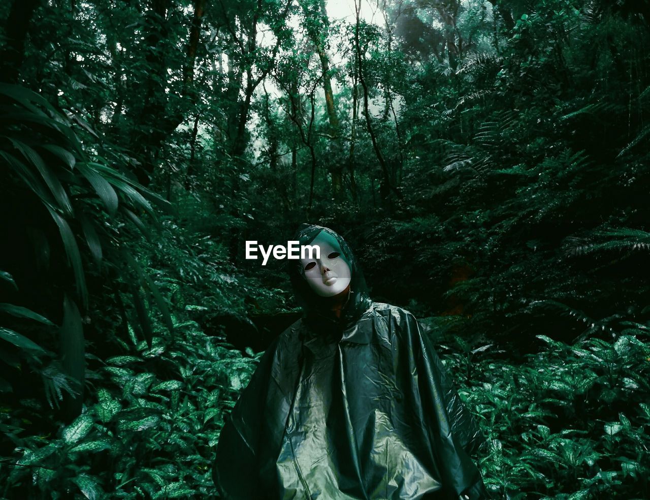 Portrait of person wearing mask amidst trees in forest