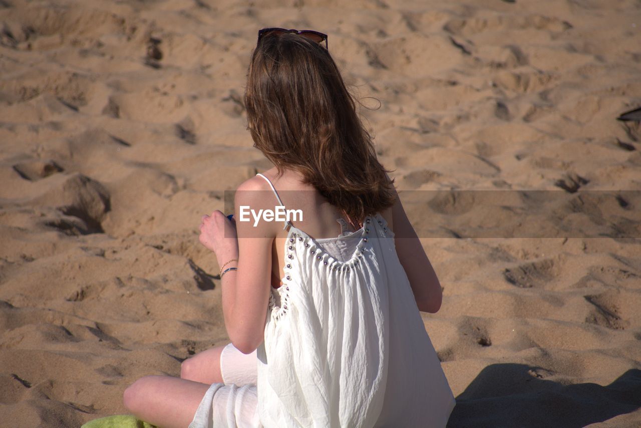 Rear view of woman sitting on beach