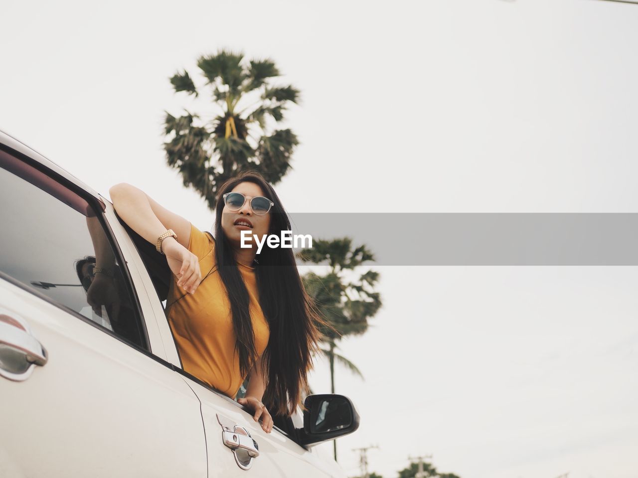 Low angle view of woman on car against clear sky