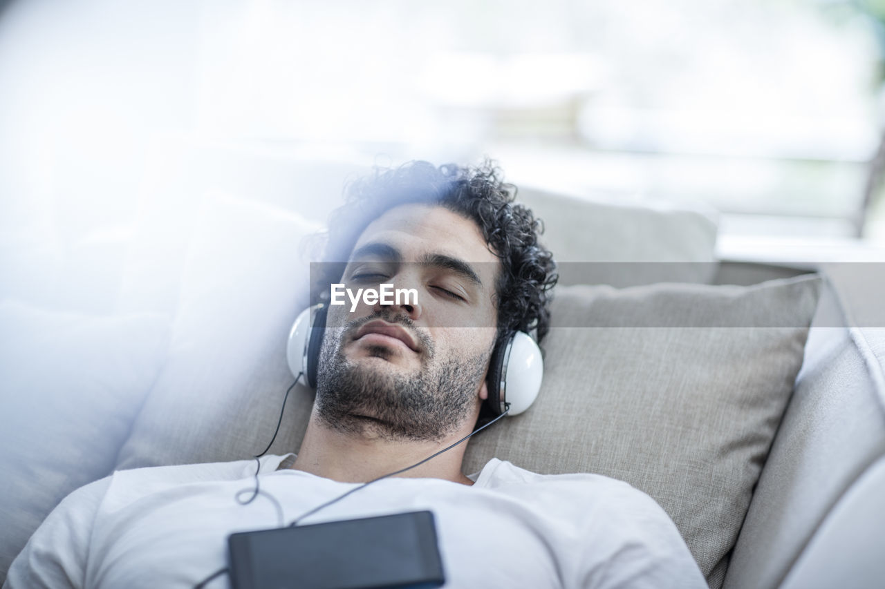 Young man relaxing on couch wearing headphones