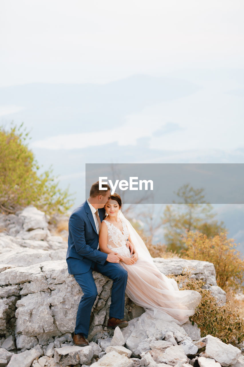 Full length of couple sitting on rock