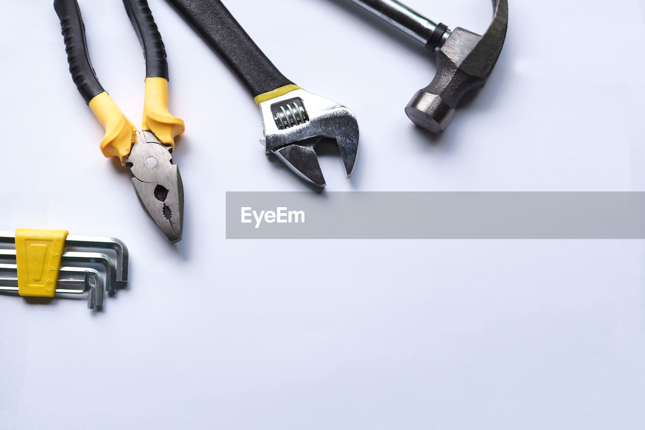 HIGH ANGLE VIEW OF TOOLS ON TABLE AGAINST WHITE BACKGROUND