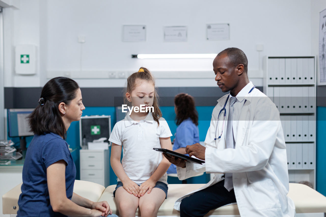 Doctor showing medical report to girl and mother