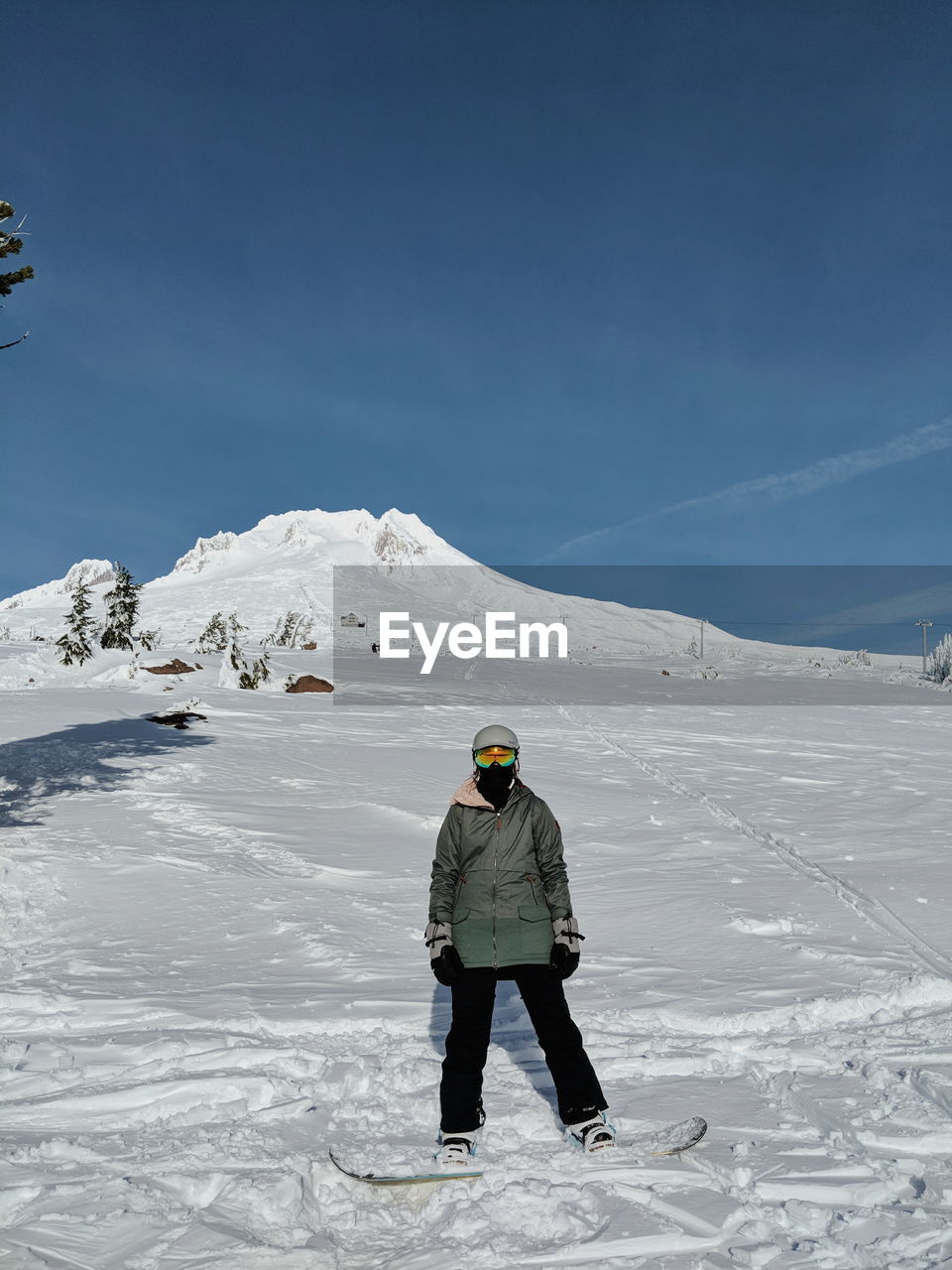 Woman standing on snowcapped mountain against sky