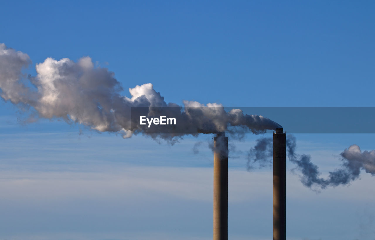 Chimneys emitting smoke against sky