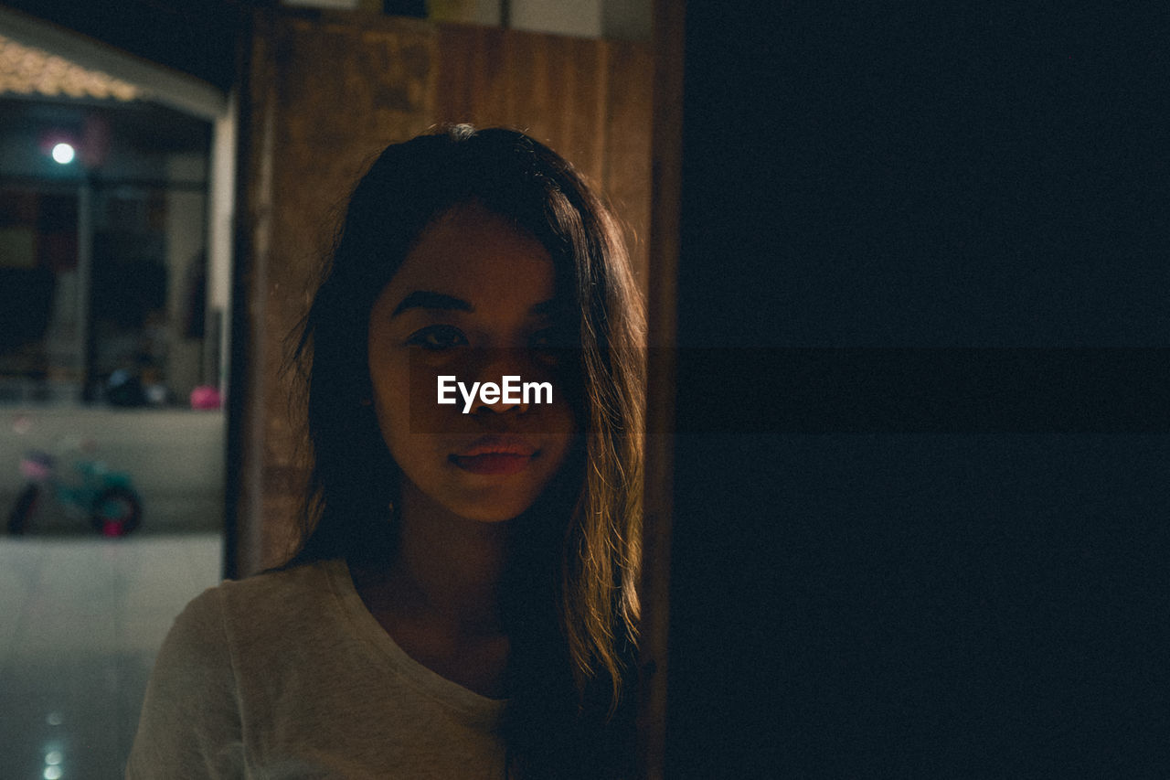 Portrait of young woman seen through window at night