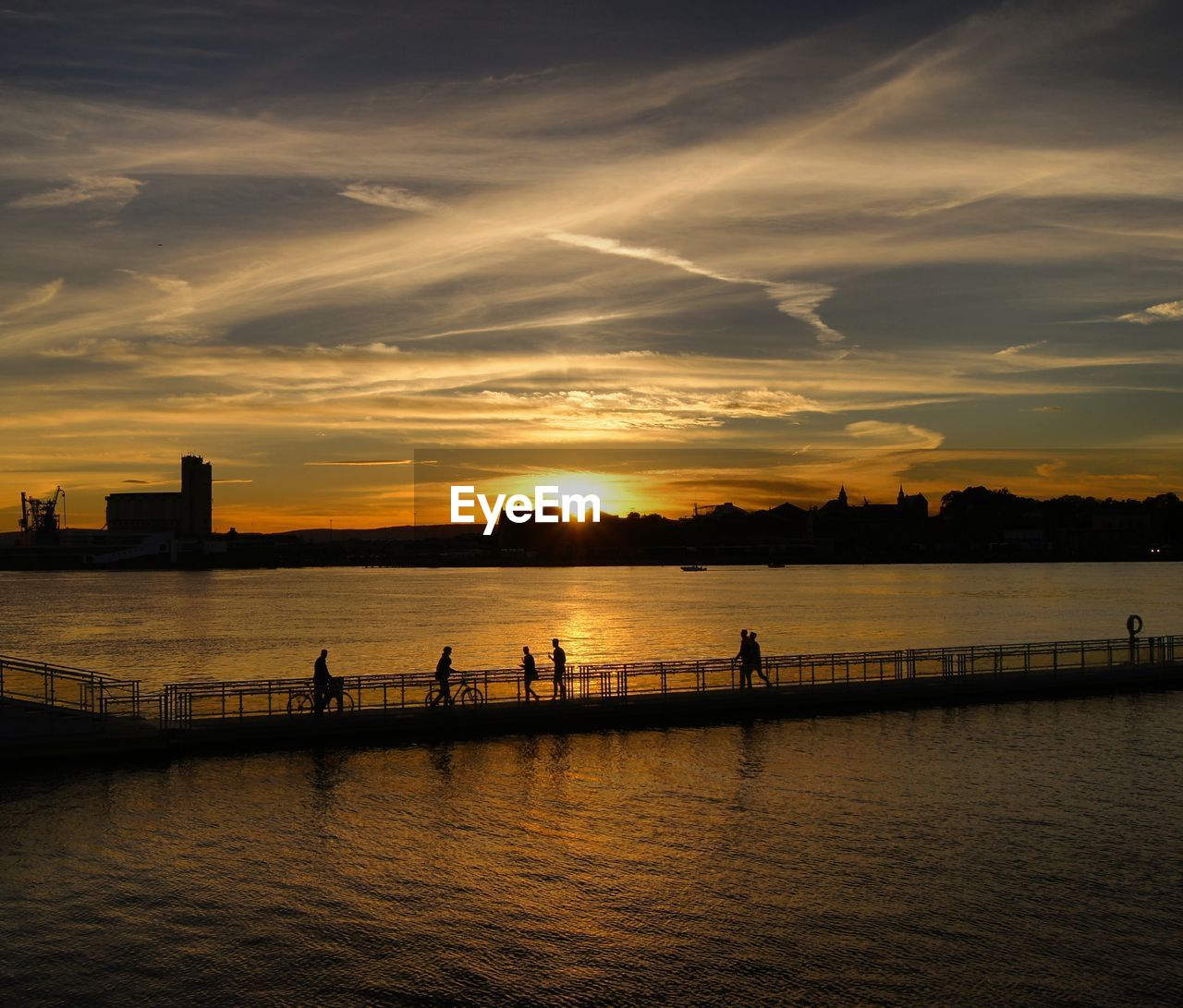 High angle view of silhouette people on footbridge over river during sunset