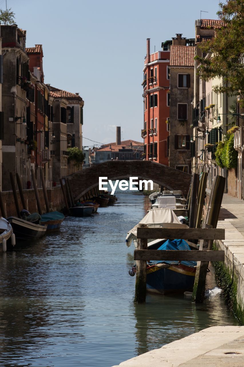Bridge over canal in city against clear sky