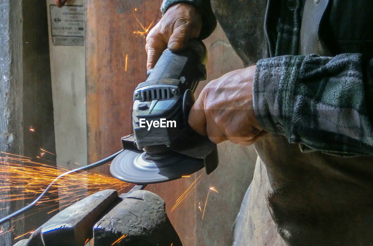 Midsection of blacksmith molding shape at workshop