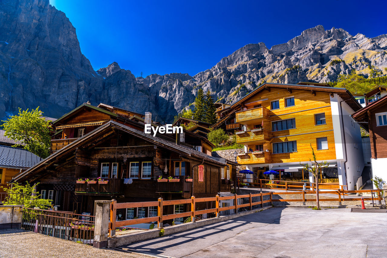 Houses against buildings and mountains against clear blue sky