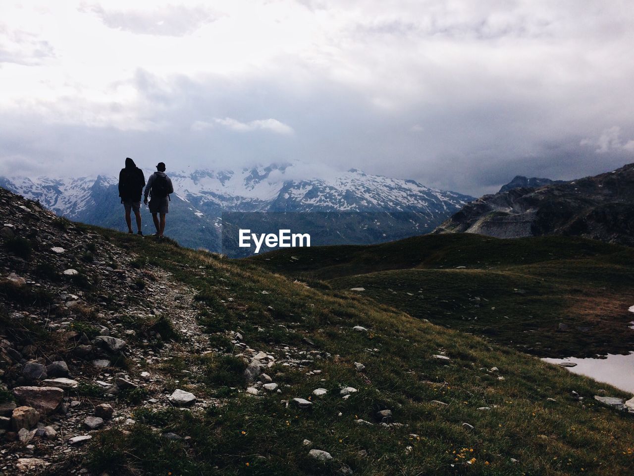 Rear view of people on mountain against cloudy sky