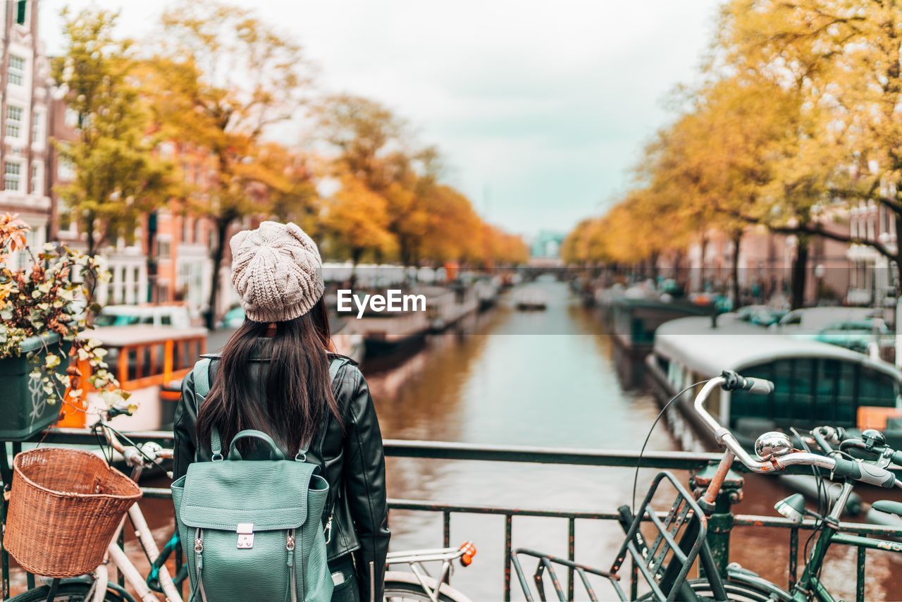 Woman standing on footbridge over canal in city