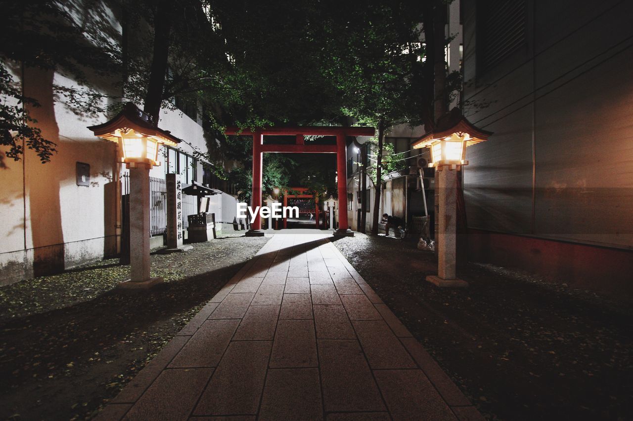 Torii gate on footpath amidst buildings