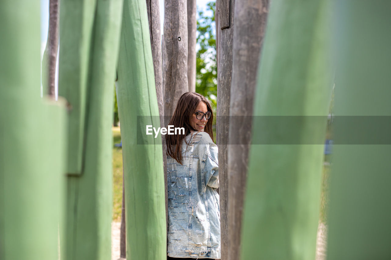 Woman standing by tree against plants