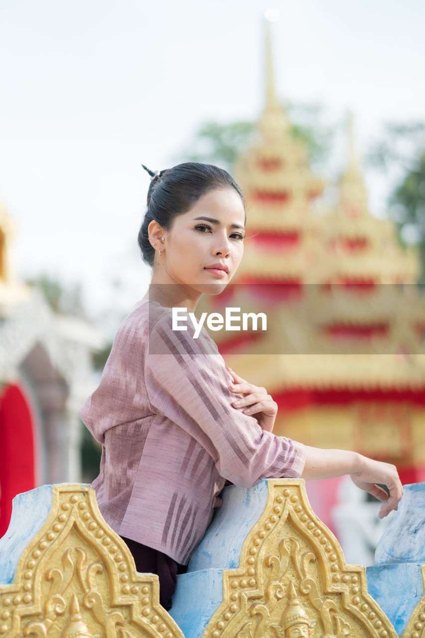 Portrait of woman standing by railing