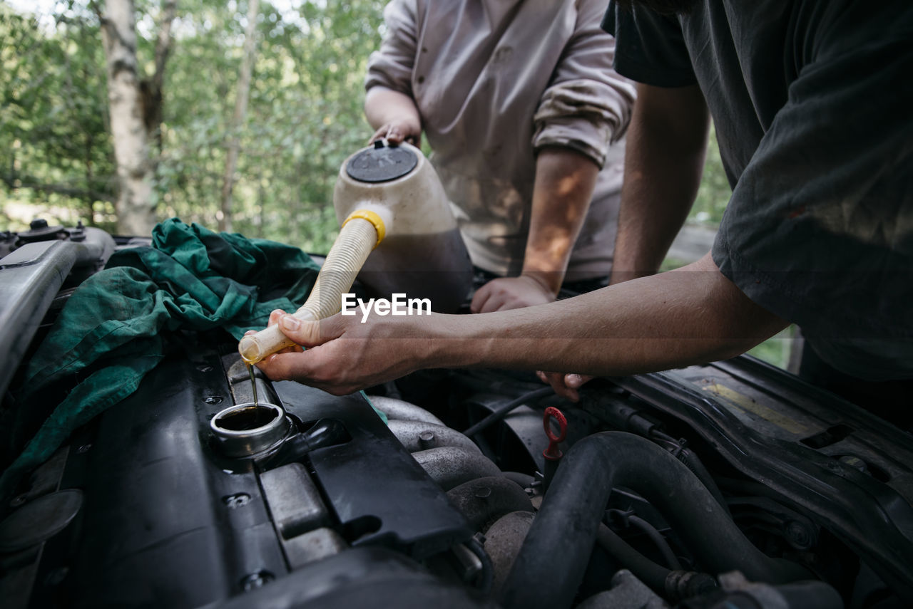 People pouring oil into engine