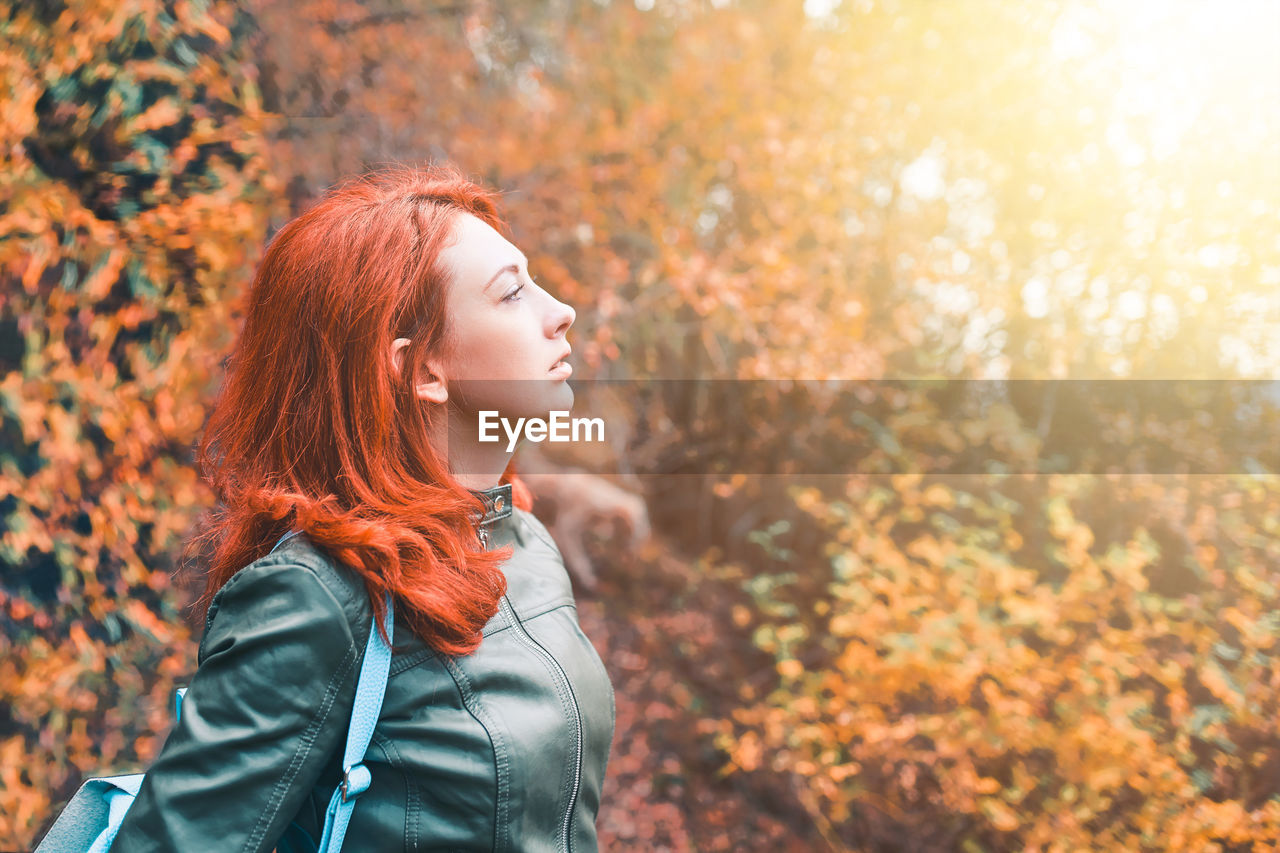 Side view of woman looking away against trees