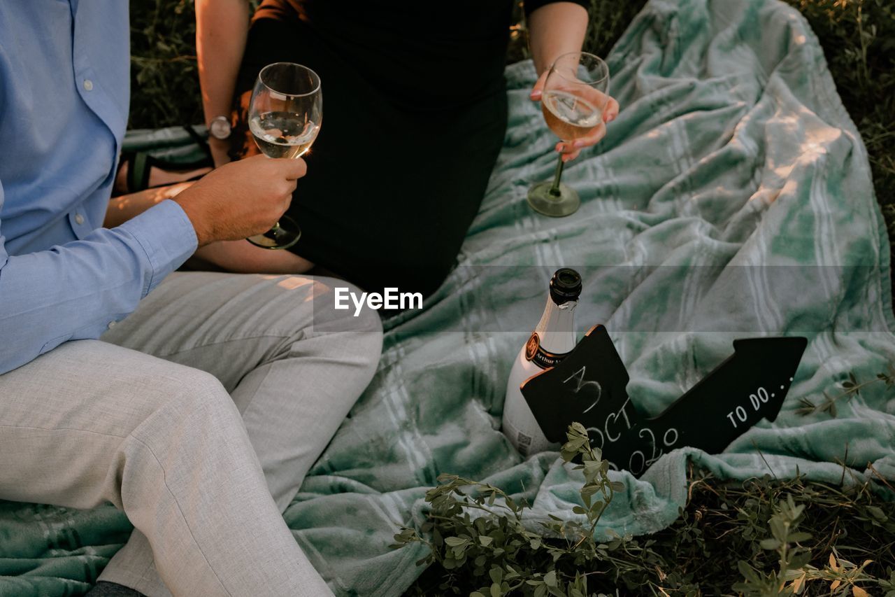 REAR VIEW OF MAN AND WOMAN HOLDING DRINK SITTING AT OUTDOOR CAFE