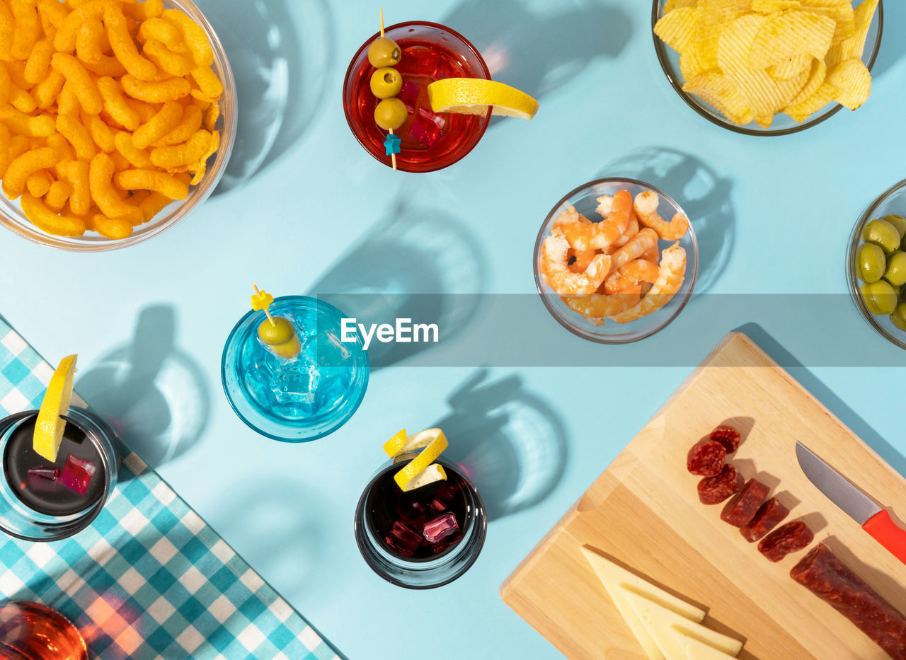 Blue table set with various snacks, appetizers and cocktails