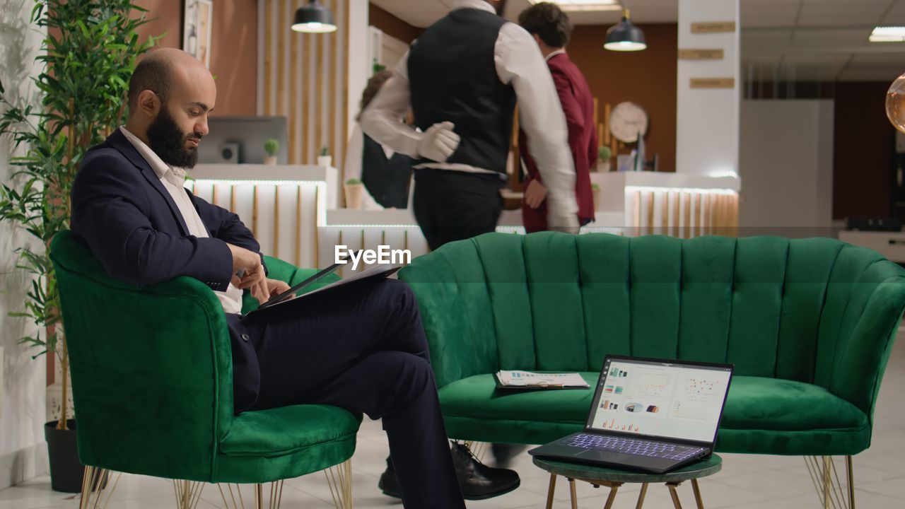 side view of woman using laptop while sitting on chair