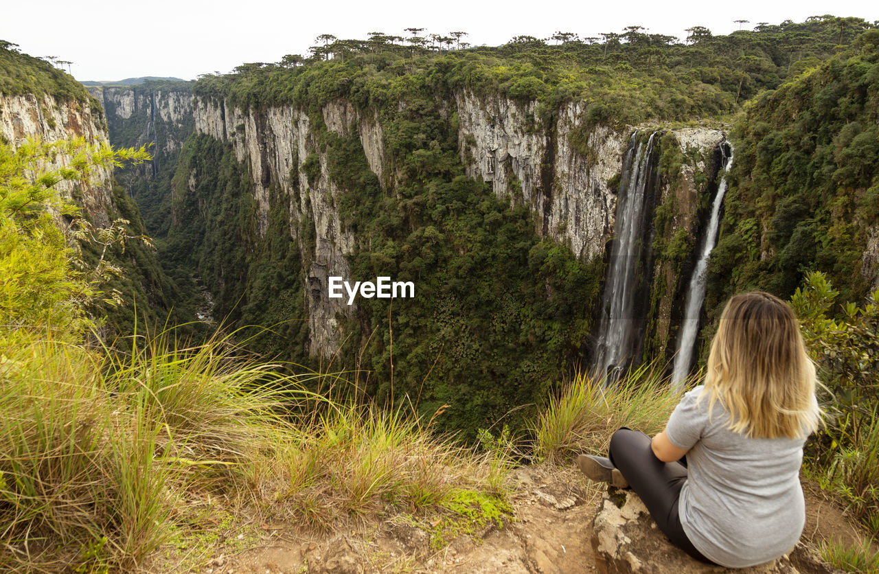 High angle view of woman sitting on cliff against mountain