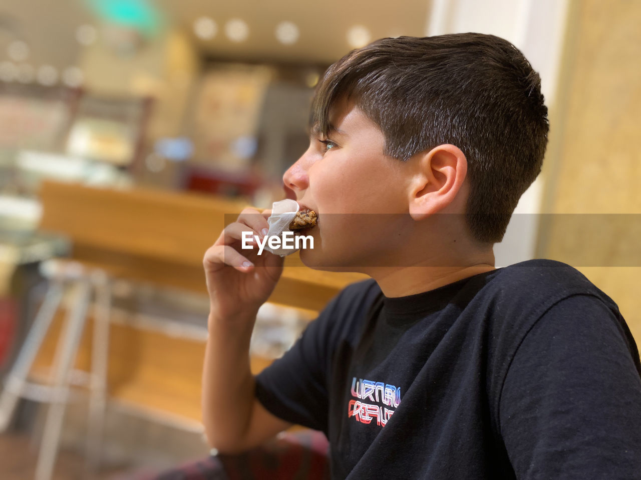 Boy eating a chocolate cookie with a napkin to avoid staining.