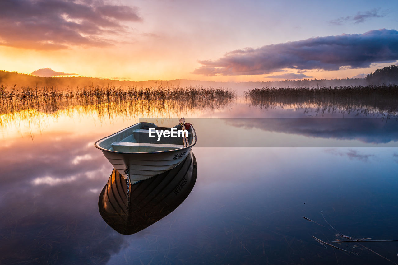Boat on still lake at sunrise, sweden.
