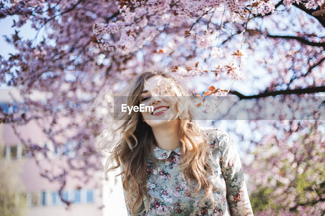 Young woman smiling in front of the spring blossom tree