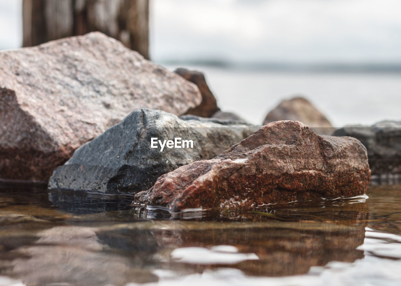 Close-up of rocks by sea against sky