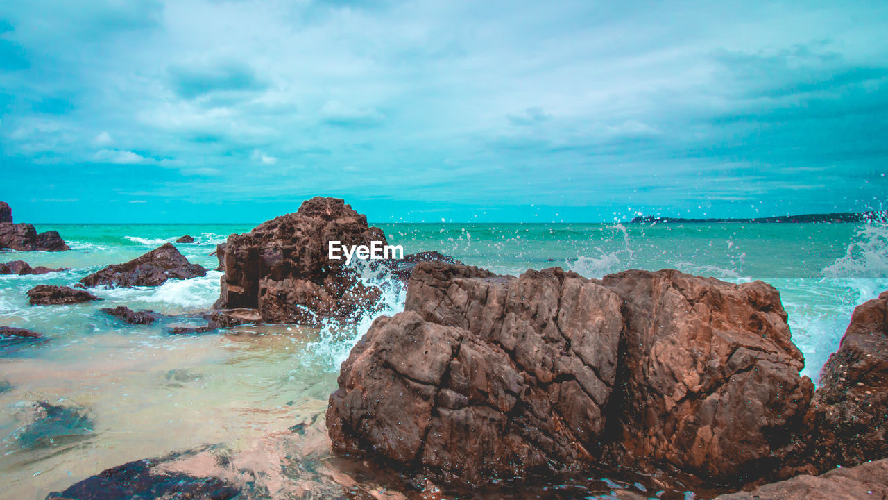 Rocks on sea shore against sky