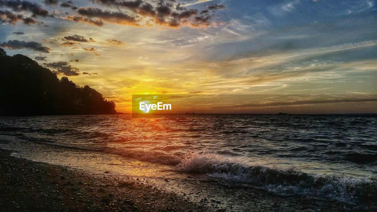 Scenic view of sea against cloudy sky during sunset