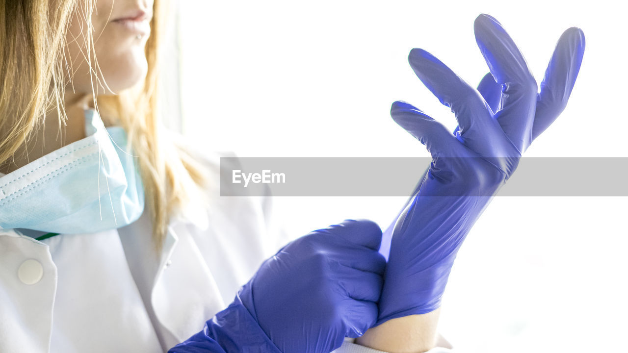 Medicine and surgery theme: female nurse putting on protective blue gloves