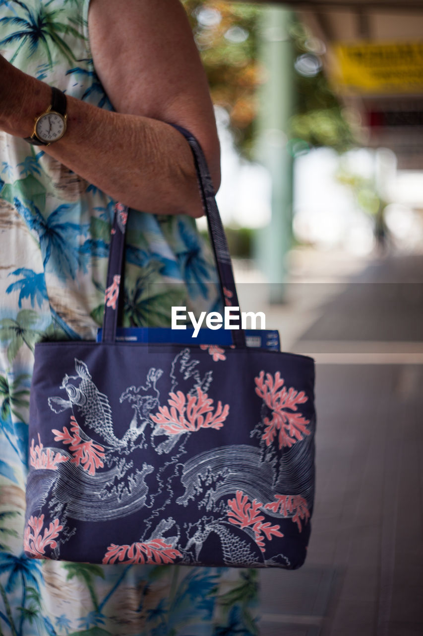 LOW SECTION OF MAN HOLDING BAG OUTDOORS