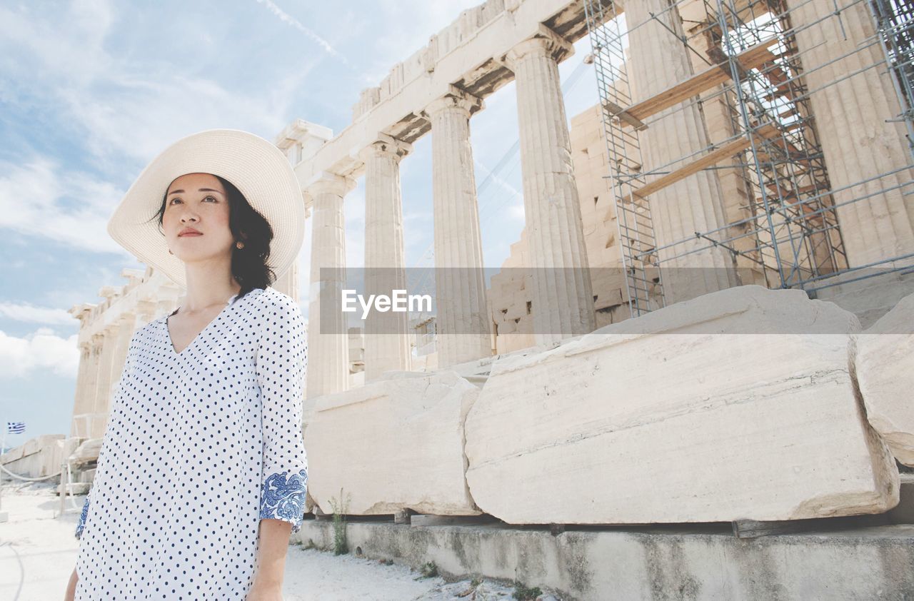 Low angle view of thoughtful young woman standing at acropolis