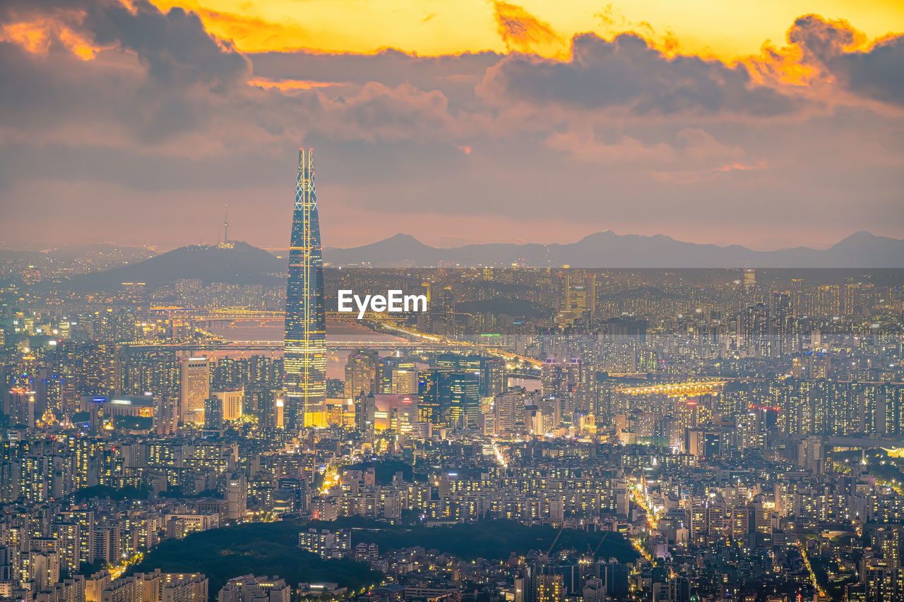 high angle view of illuminated cityscape against sky during sunset