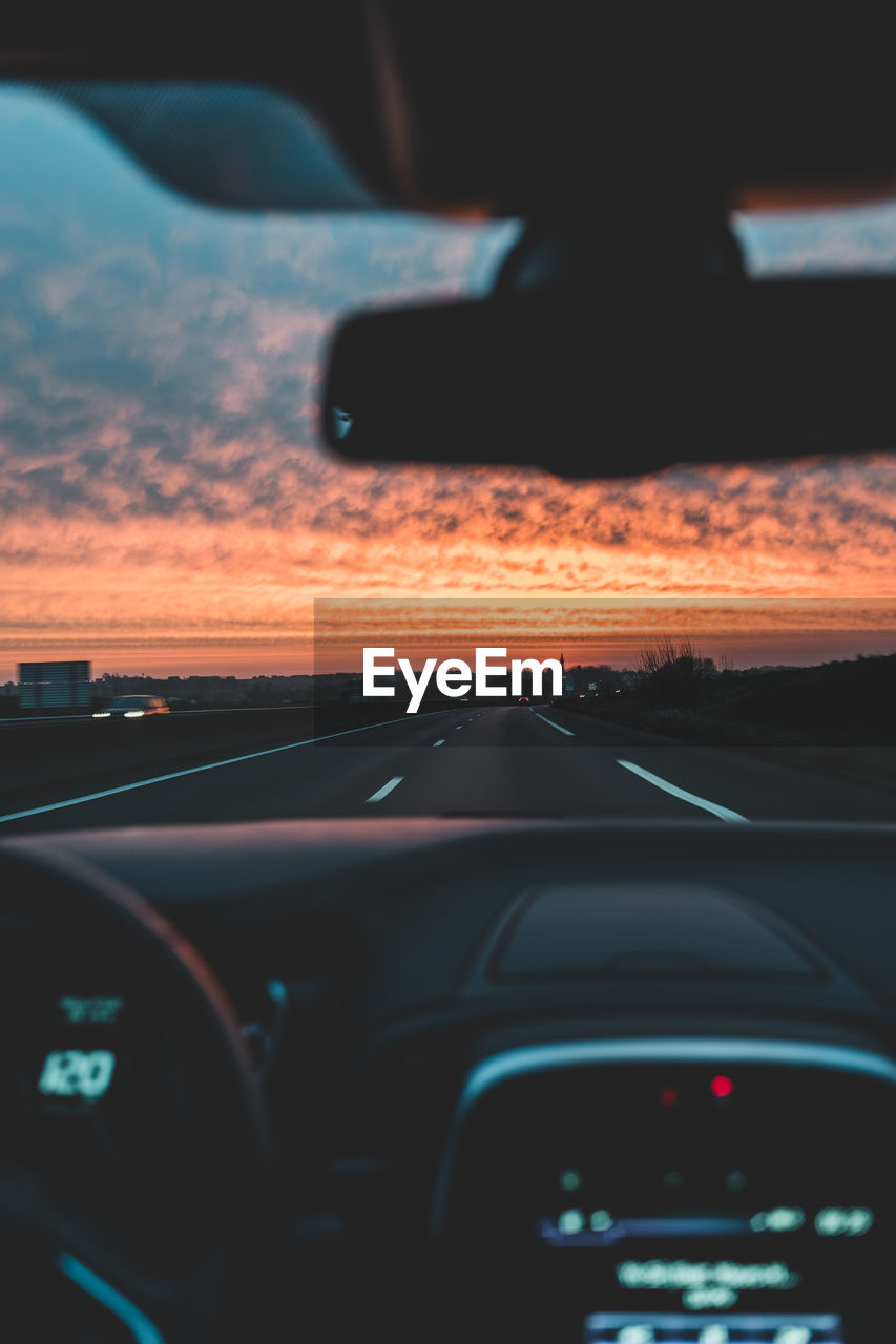 Road seen through car windshield during sunset