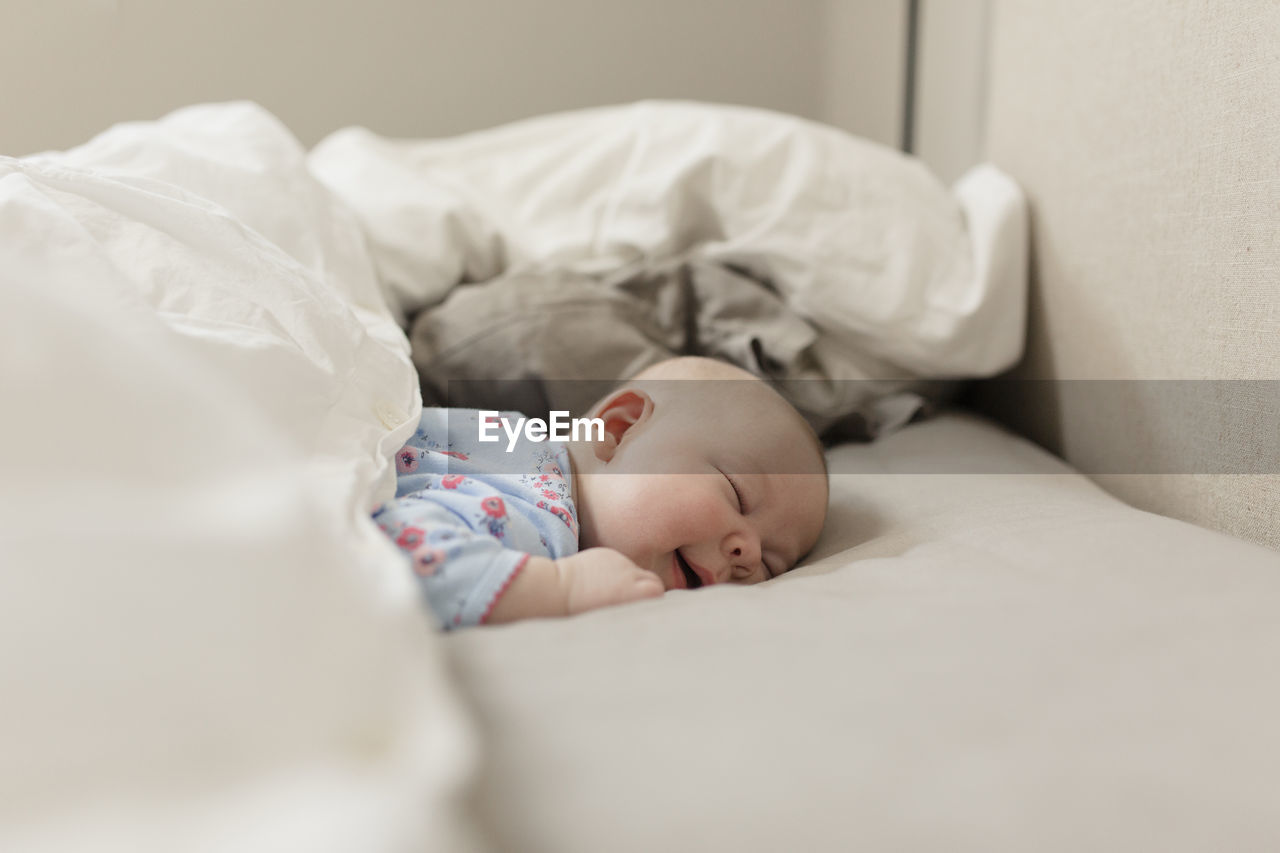 Cute baby girl sleeping on bed at home