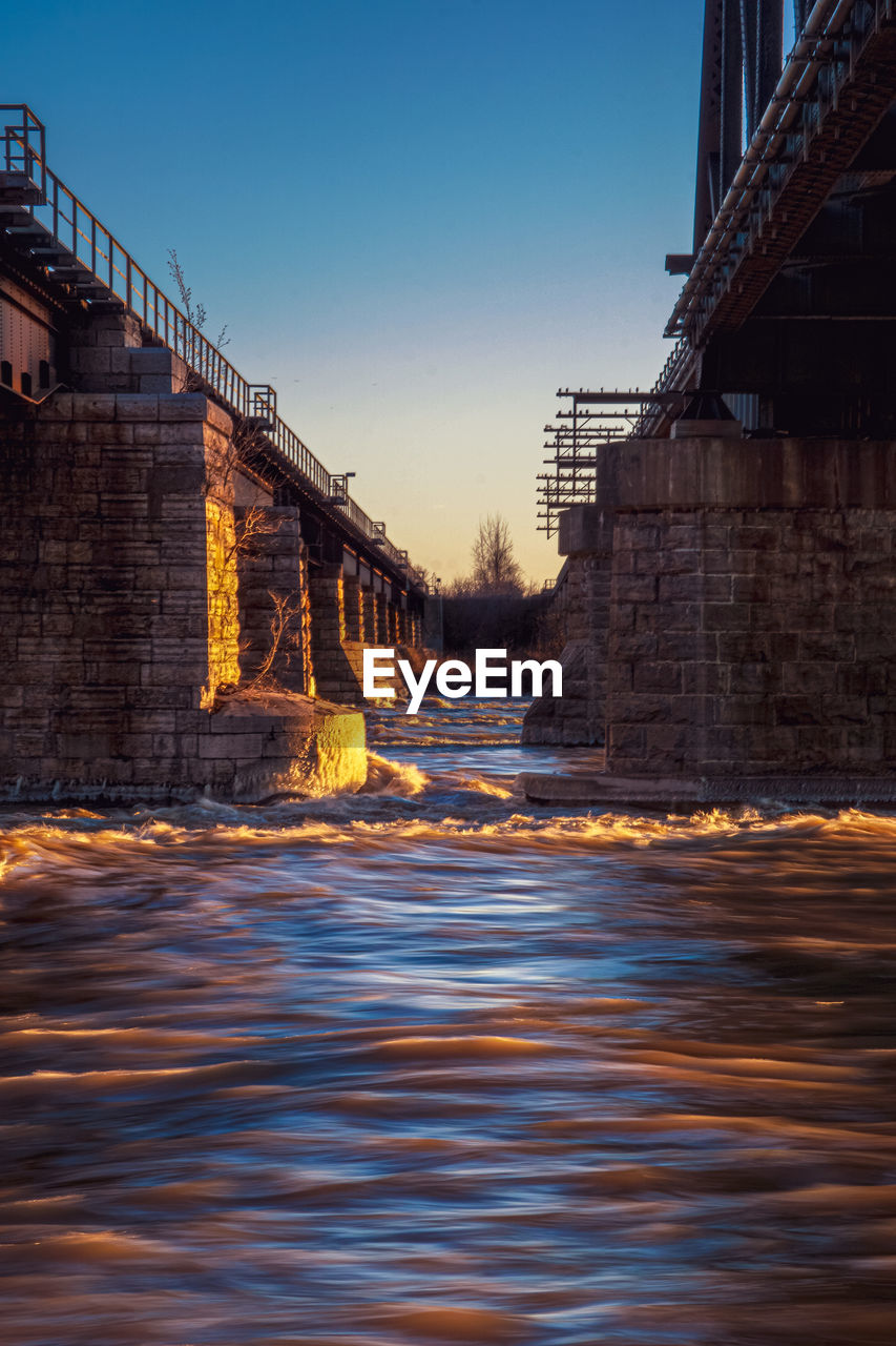 Bridge over river against clear sky at dusk