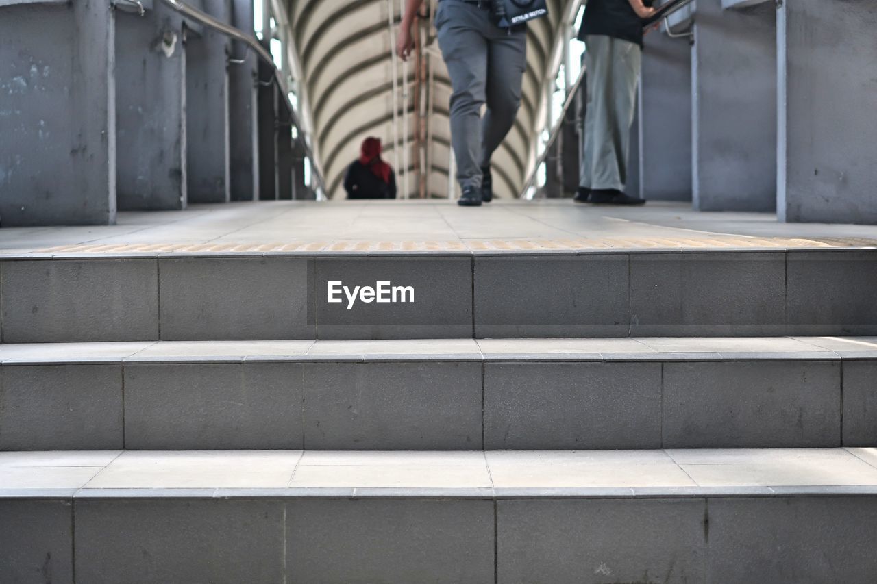 LOW SECTION OF MAN WALKING ON STAIRCASE